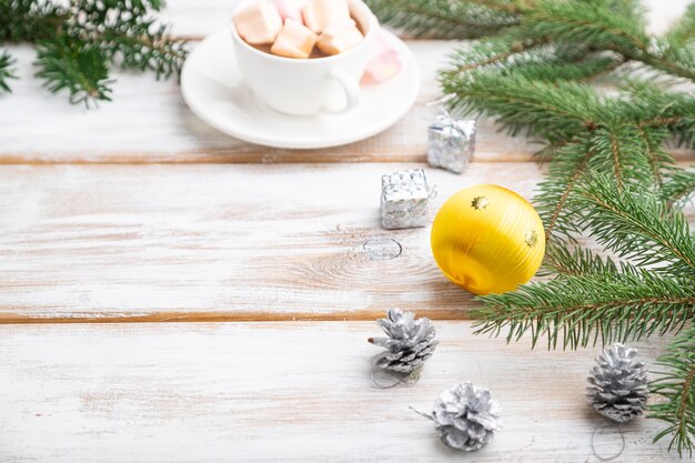 Natal ou composição. Decorações, bolas, cones, ramos de abeto e abeto, xícara de café na mesa de madeira branca.