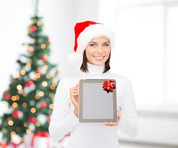 natal, tecnologia, presente e conceito de pessoas - mulher sorridente no chapéu de ajudante de papai noel com computador tablet pc de tela em branco sobre a sala de estar e o fundo da árvore de natal