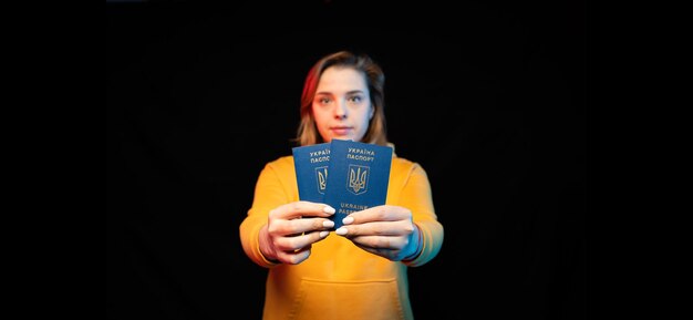 Nationaler Pass der Ukraine Schönes ukrainisches Mädchen mit Regierungspass in den Händen auf schwarzem Hintergrund