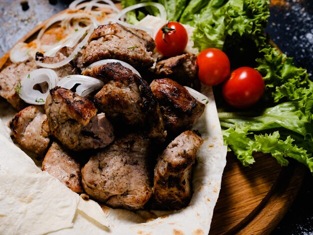 Nationales kaukasisches Essen. Gegrillter Schaschlik mit Salattomaten und Zwiebeln mischen auf Lavash.