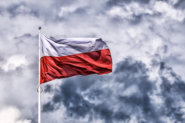 Nationalflagge Polens weht auf einem dunklen, bewölkten Himmelshintergrund HDR-Effekt