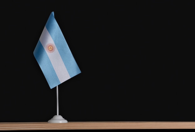 Nationalflagge von Argentinien auf dem Tisch auf Schwarz. Fahnenmast.