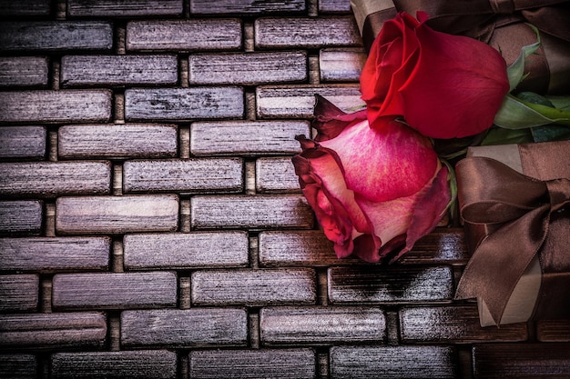 Natürlich duftende Rosen verpackte Geschenkboxen auf geflochtener Holzmatte