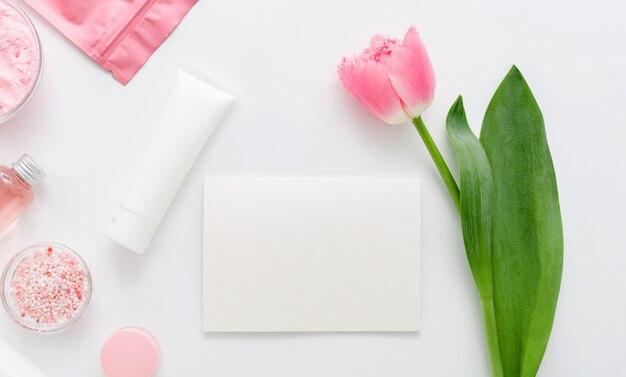 Natürliche Bio-Kosmetikprodukte mit rosa Tulpenblüte. Weiße leere Modellkarte mit Platz für Text. Kosmetik für Bad Spa, Hautpflege, Flat Lay