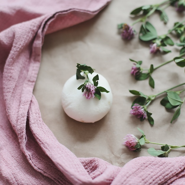 Natürliche Bio-Seife mit Blumen und rosa Handtuch auf Kraftpapierhintergrund Draufsicht mit Exemplar