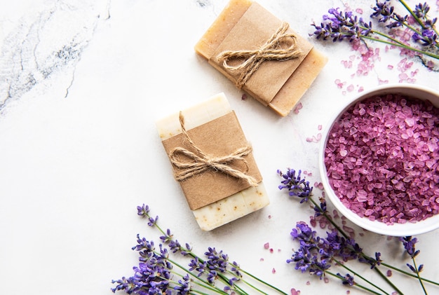 Natürliche Bio-SPA-Kosmetik mit Lavendel. Flach gelegtes Badesalz und Lavendelblumen auf Marmorhintergrund. Hautpflege, Schönheitsbehandlungskonzept