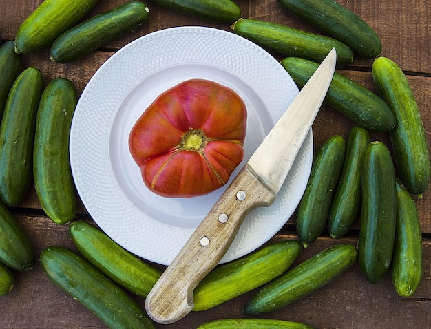 Natürliche Gartengurken und natürliche große Dorftomaten nebeneinander auf dem Holzboden