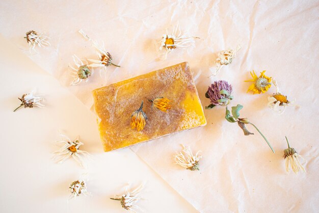 Natürliche handgemachte Seife mit Kamillenblumenextrakt. Herum sind getrocknete Blumen.