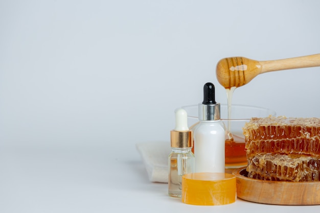 Natürliche hautpflegeseife und -serum mit honig und waben auf weißer oberfläche.