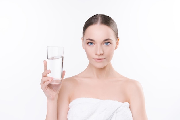 Natürliche junge Frau im weißen Handtuch hält ein Glas Wasser Konzept Wasserhaushalt