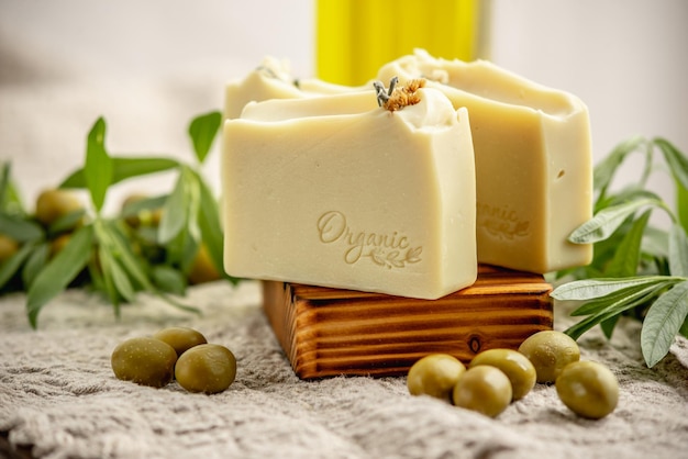 Natürliche kastilische Seife auf einer hölzernen Seifenschüssel eine Flasche Olivenöl und Olivenzweig hochwertige Bio-Kosmetika und Hautpflege