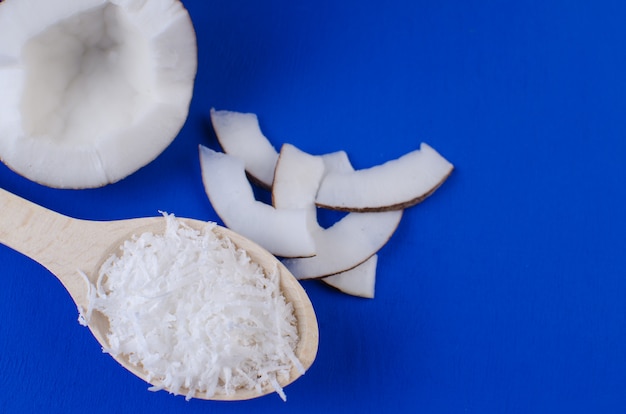 Natürliche Kokosmilch, Kokosnussspäne, Kokosnusschips auf blauem Grund. Das Konzept der gesunden Ernährung.