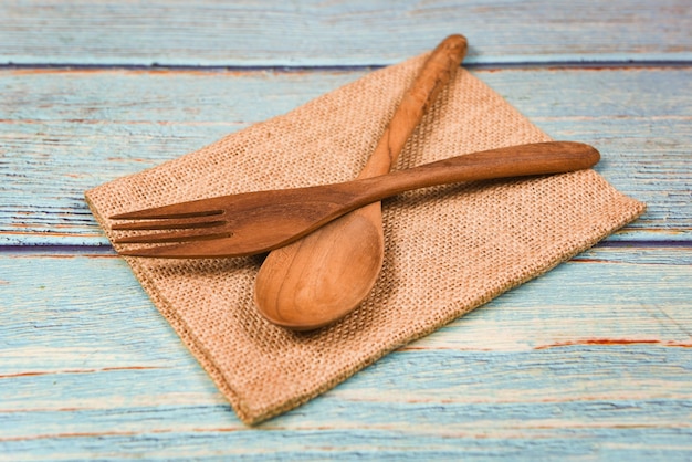 Natürliche Küche bearbeitet Holzprodukte - Küchengeräte mit hölzernem Löffel und Gabel auf Sack im Abendtischhintergrund