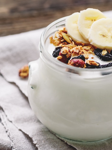 Natürlicher hausgemachter Joghurt im Glas mit Müsli und Früchten