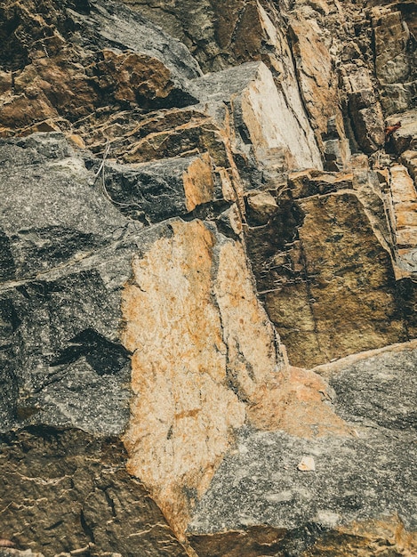 Natürlicher Hintergrund Nahaufnahme umrandete schäbige Klippenrisse Graubraune Steinfelsenstruktur der Berge Vintage und verblasste matte Stilfarbe in getöntem Foto Konzept des geologischen Bergsteigens oder harter Arbeit