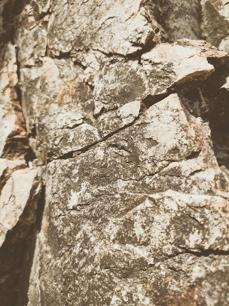 Natürlicher Hintergrund Nahaufnahme umrandete schäbige Klippenrisse Graubraune Steinfelsenstruktur der Berge Vintage und verblasste matte Stilfarbe in getöntem Foto Konzept des geologischen Bergsteigens oder harter Arbeit