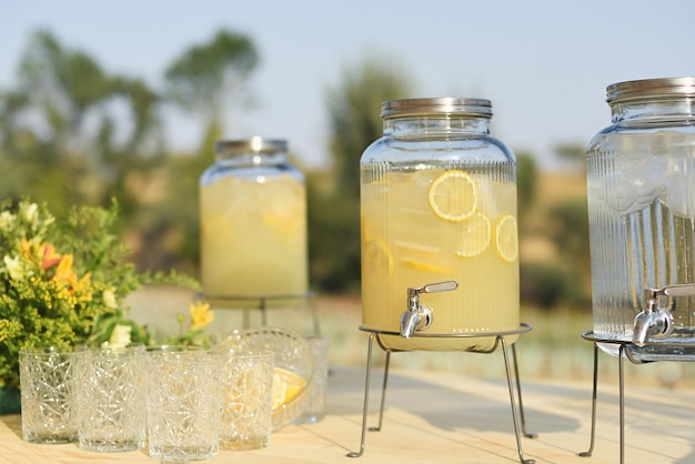 Foto natürlicher limonadenspender mit vintage-glasbechern im freien