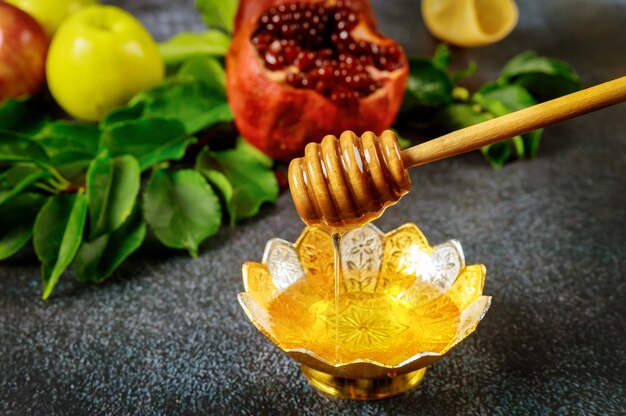 Natürlicher süßer Honig mit hölzernem Honigstab und Granatapfel.