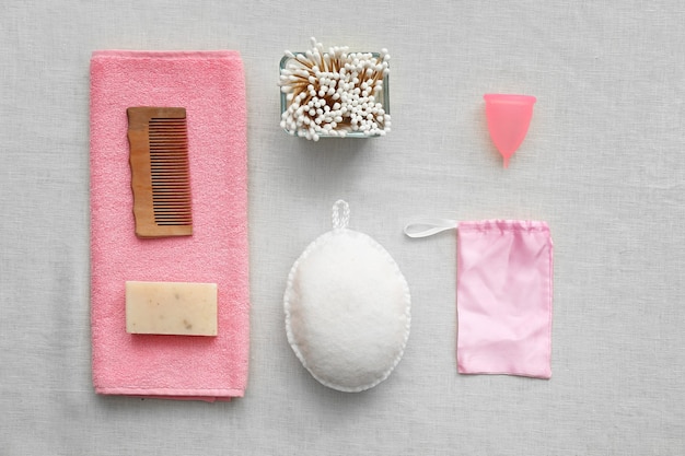 Natürliches Badezubehör mit Menstruationstasse auf Grau. Zero-Waste-Konzept