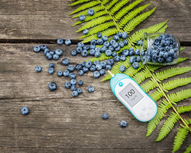 Natürliches Blutzuckermessgerät aus wilden Blaubeeren und Farnblätter auf einem Holztisch