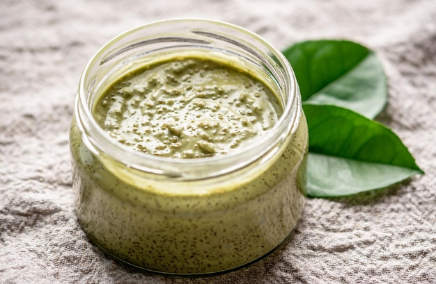 Natürliches grünes Scrub mit Zucker in einem Glaskrug auf dem Hintergrund von Stoff und Blättern Konzept der Bio-Kosmetik und Hautpflege