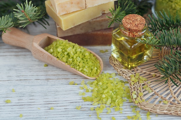 Natürliches Meersalz und handgemachte Seife mit Kiefernzweig auf weißem Holz.