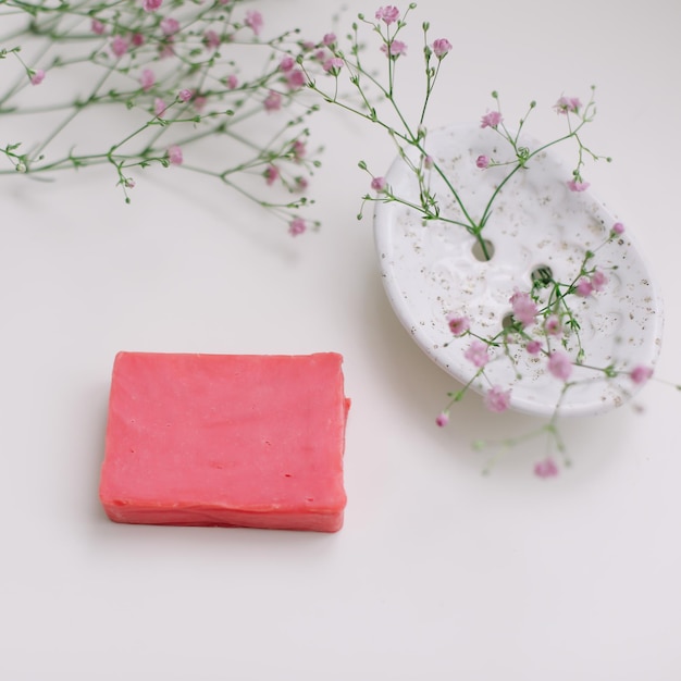 Natürliches Seifenstück mit keramischer Seifenschale und Blumen-Spa-Bio-Konzept