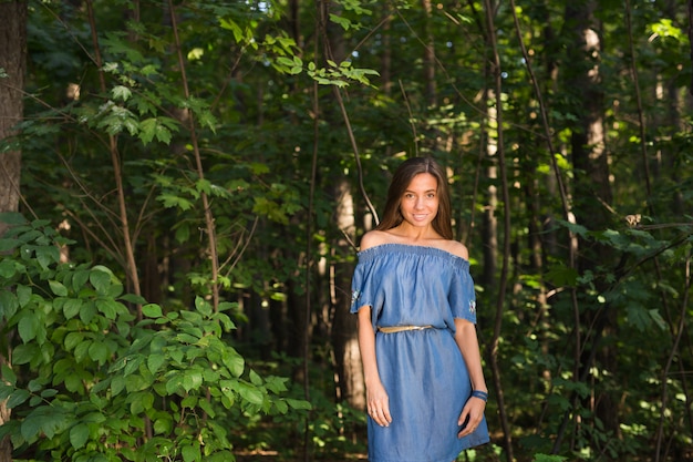 Natur, Menschen und Sommerkonzept - Porträt der jungen Frau, die den grünen Wald genießt.