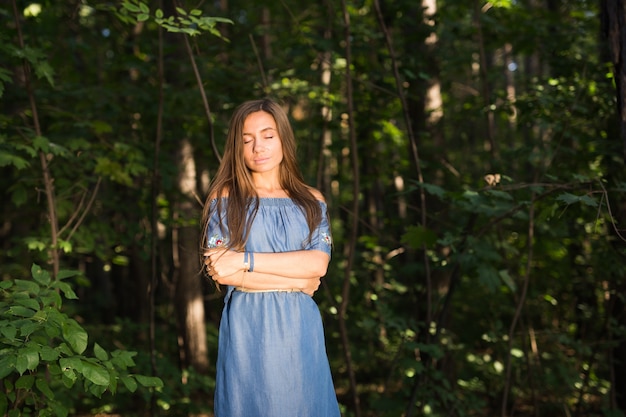 Natur, Menschen und Sommerkonzept - Porträt einer jungen Frau, die den grünen Wald genießt.