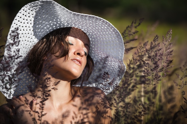 Natur, Schönheit, Jugend und gesundes Lebensstilkonzept. Junge Frau im weißen Hut auf Naturrasenhintergrund. Mädchen, das draußen die Natur genießt.