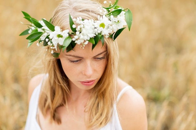 Foto natur, sommerferien, urlaub und personenkonzept - gesicht einer glücklichen frau im blumenkranz