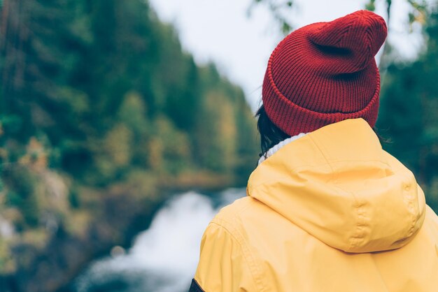 Foto uno con la naturaleza hacia atrás vista de mujer irreconocible mirando al bosque y cascada mujer en brillante