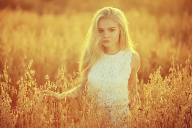 naturaleza de cabello largo rubio verano / niña adulta feliz con desarrollo en el viento cabello largo y rubio en el campo de verano