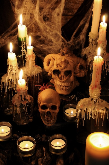 Naturaleza muerta de calaveras en el libro junto al ambiente de velas concepto de magia negra