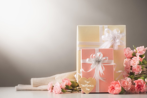 Naturaleza muerta con flores de clavel dulce y regalo en la mesa, concepto del día de la madre