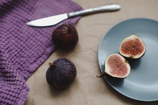 Naturaleza muerta con higos frescos maduros con un cuchillo y textiles de color púrpura en una vista de mesa