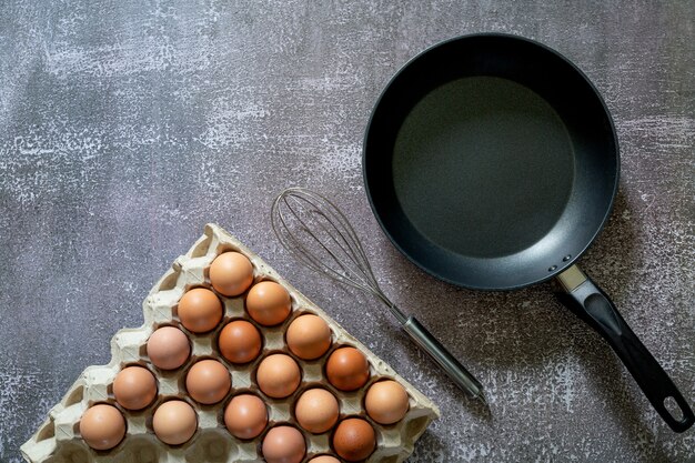 Naturaleza muerta con huevos y sartén en la vista superior de la mesa de madera