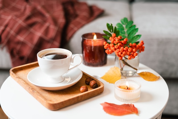 Naturaleza muerta libro vela baya de serbal y una taza de té o café en la sala de estar en una mesa en casa