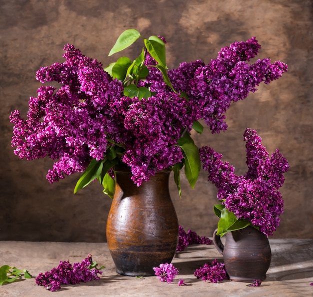 Naturaleza muerta con ramas florecientes de lilas en jarrones