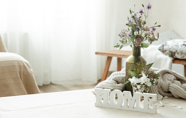 Naturaleza muerta con un ramo de flores, un libro y una palabra decorativa de madera para el hogar.