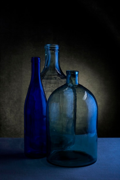 Naturaleza muerta con tres botellas de vidrio sobre un fondo oscuro