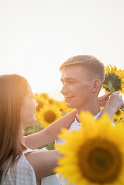 Naturaleza otoñal. Joven pareja romántica caminando en el campo de girasol al atardecer