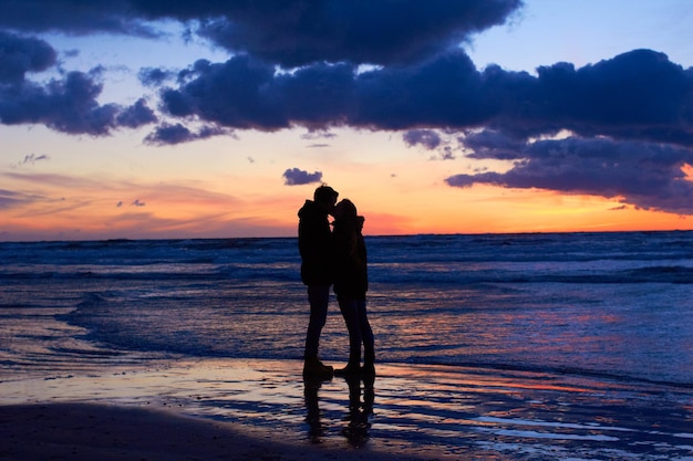 Naturaleza preparando el escenario para el romance Silouehette de una pareja besándose en la playa al atardecer
