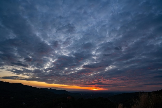 Naturaleza puesta de sol paisaje escena vista panorámica vista natural para usar en segundo plano o concepto de desarrollo ambiental y sostenible El sol cayendo sobre el cielo nublado y la tierra montañosa local