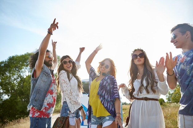 naturaleza, verano, cultura juvenil y concepto de la gente - felices jóvenes amigos hippies bailando sobre un minivan al aire libre