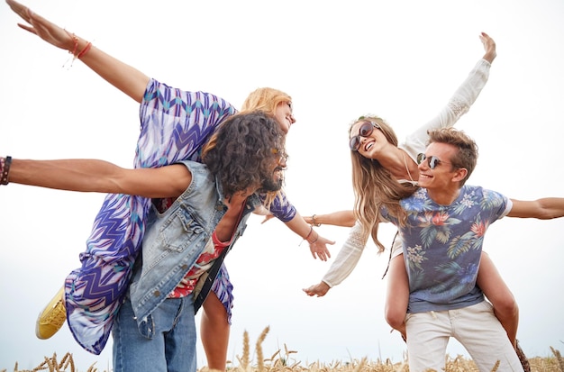 naturaleza, verano, cultura juvenil y concepto de la gente - felices jóvenes amigos hippies divirtiéndose en el campo de cereal