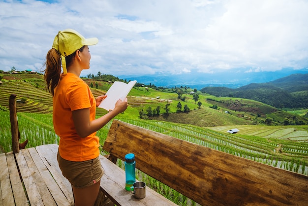 Natureza asiática do curso da mulher Viajar relaxar. Permanente lendo o livro na varanda da casa. no verão.