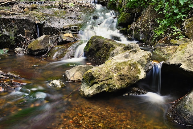 Natureza bonita com um rio de rochas e floresta. fundo colorido ao ar livre com água.