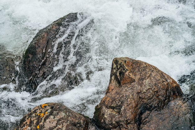 Natureza de quadro completo com pedregulhos no riffle de água do rio da montanha. fluxo de água poderosa do riacho de montanha. pano de fundo texturizado de fluxo rápido de riacho de montanha com corredeiras. close-up de pedras grandes