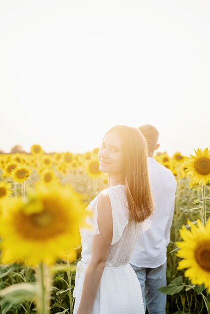 Natureza do outono. Jovem casal romântico caminhando em um campo de girassol ao pôr do sol